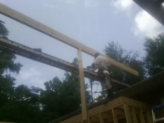 Carpenter setting a ridge beam over a new addition frame — Ice Dam Removal by Roofing Brothers in Tuxedo Park