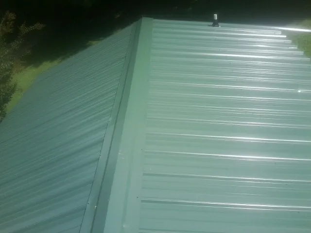 New green metal panels meeting at the ridge of a roof — Flat Roof Repair work by our crew in Tuxedo Park