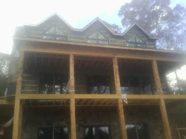 Dormers and porch framing on a large log home under construction — Roof Coating work by our crew in Tuxedo Park