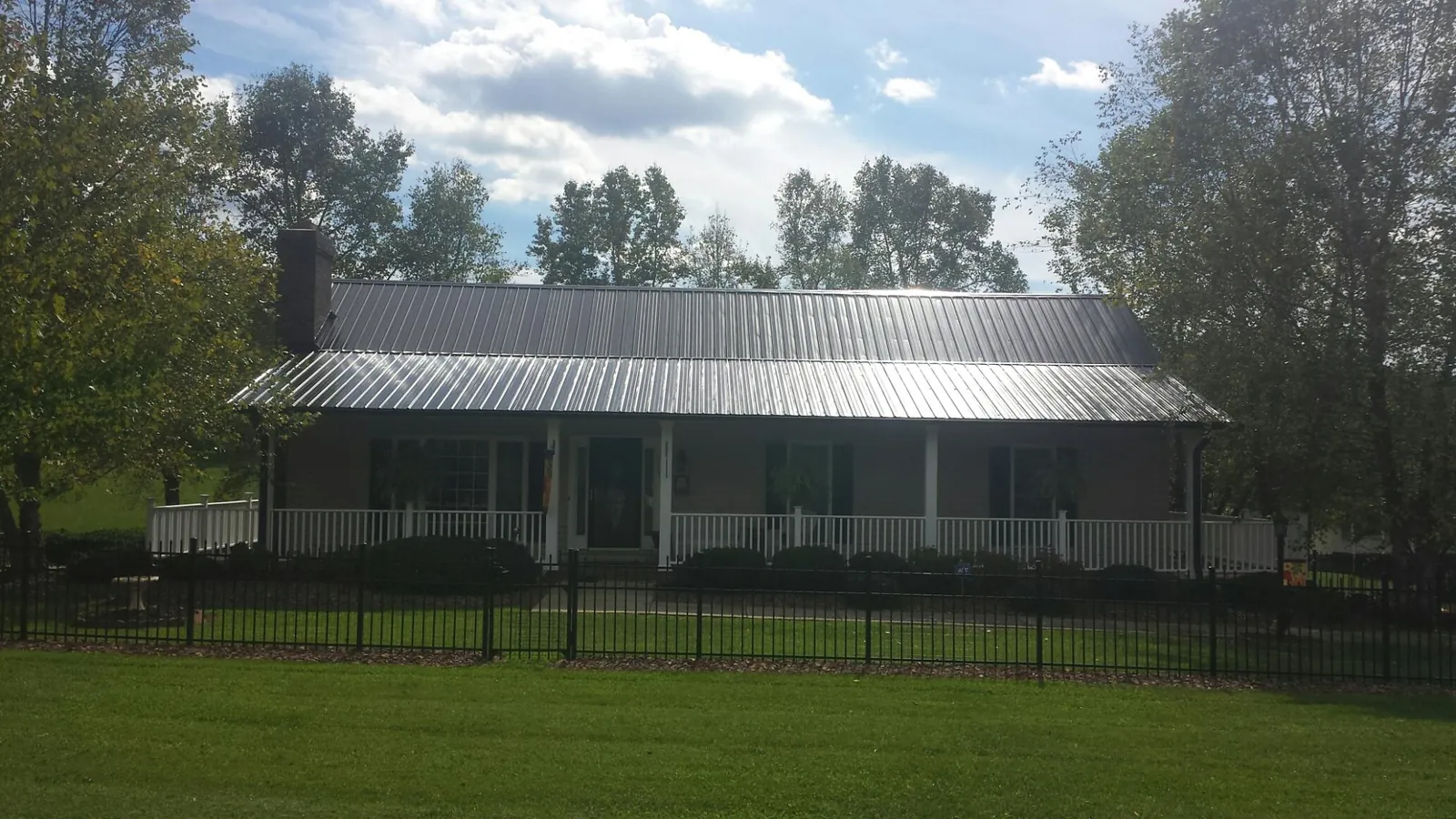Gray metal roof on a brick ranch with a full width front porch — Gutter Guard Installation work by our crew in Tuxedo Park