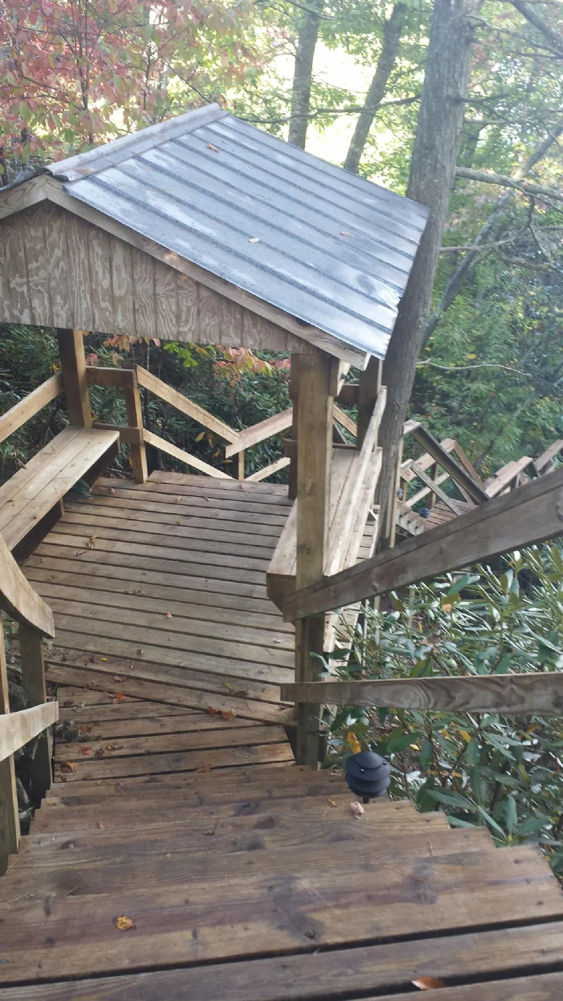 Metal roofed shelter over wooden steps on a wooded walkway — Skylight Repair & Installation work by our crew in Tuxedo Park